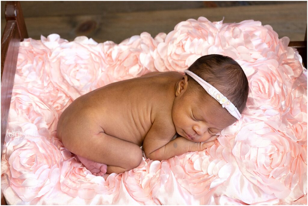 newborn girl on pink rosette blanket
