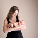 mom in black dress holding newborn