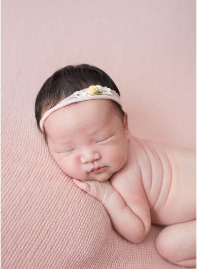 newborn girl on light pink blanket