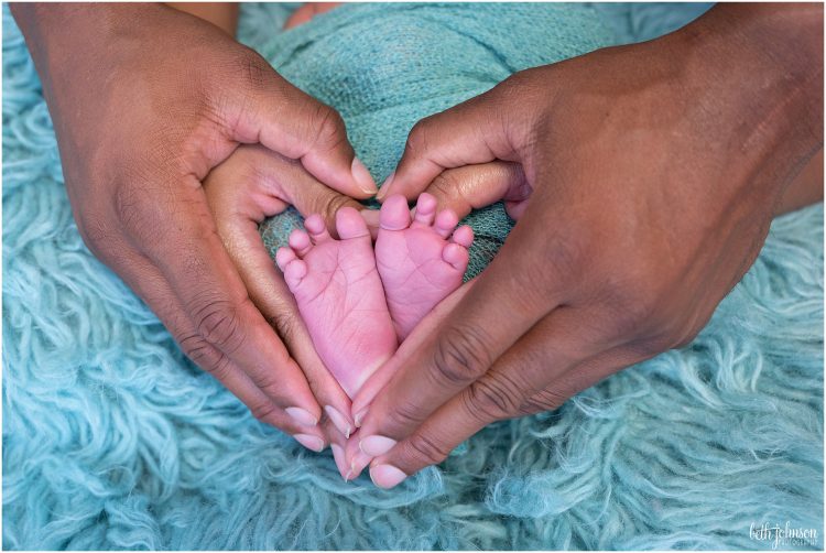 newborn with parents hands in heart shape