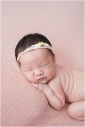 newborn girl on light pink blanket