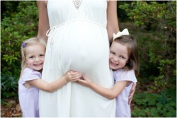 two girls hugging moms pregnant belly