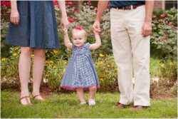 toddler holding mom and dads hands outside