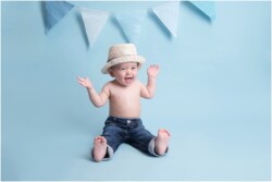 baby boy with hat on blue bunting backdrop
