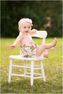 baby in flower romper sitting backwards on chair