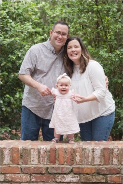 parents helping baby stand on bricks