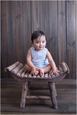 baby in jon jon romper sitting on wooden stool