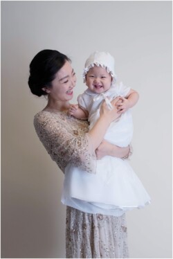 mom holding baby daughter in baptism gown