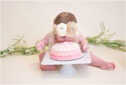 baby girl putting her face in her birthday cake