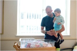 dad and big brother looking at newborn sister
