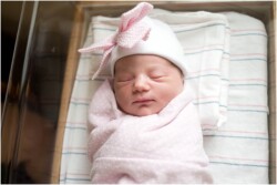 newborn girl in hospital with bow hat