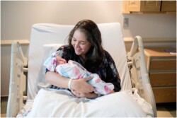mom smiling at newborn baby in hospital