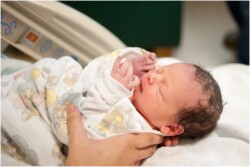 mothers hands holding baby after birth