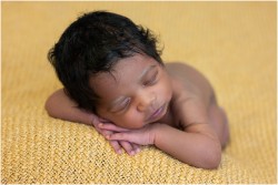 newborn baby with head of hair on yellow blanket