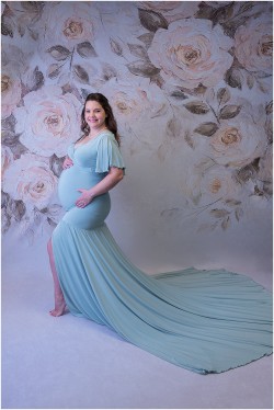maternity photo in sage dress on floral backdrop