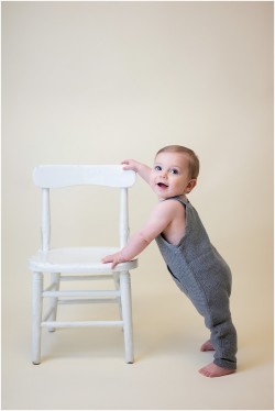 baby boy standing holding chair